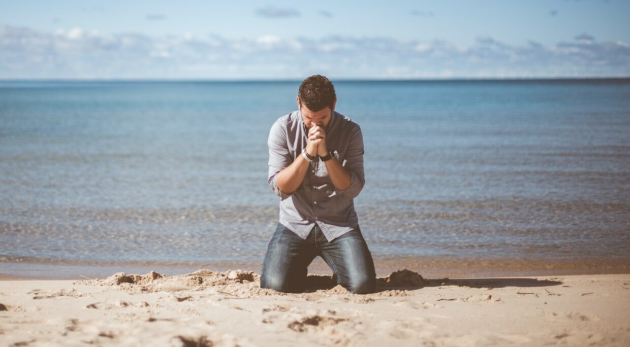 man kneeling down near shore