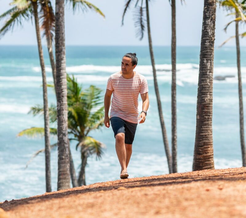 a man running on the beach with palm trees in the background
