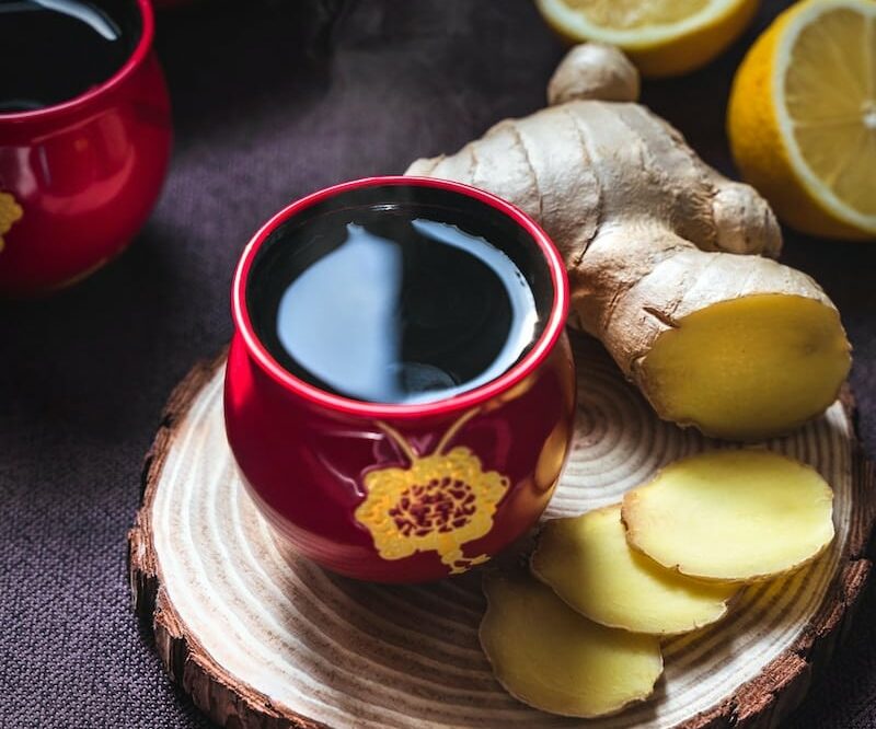 sliced lemon on red ceramic saucer beside red ceramic mug with black liquid