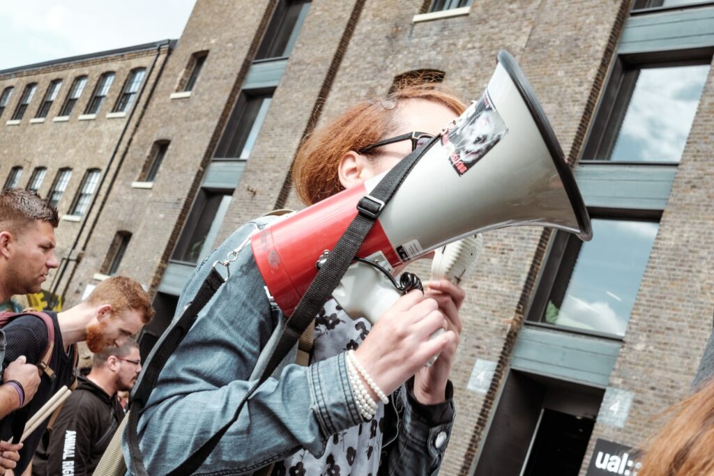 woman holding red and white megaphone standing near building