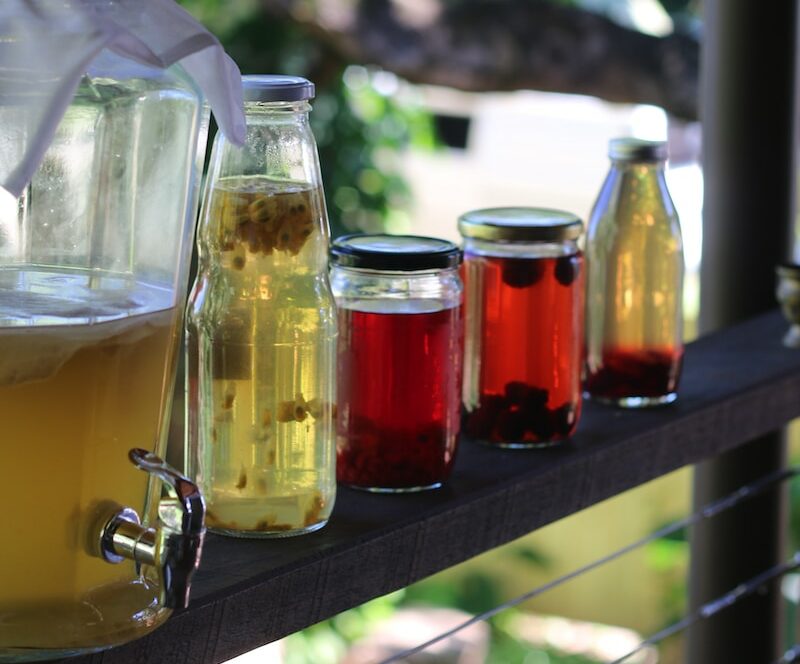 a row of jars filled with liquid sitting on top of a wooden shelf